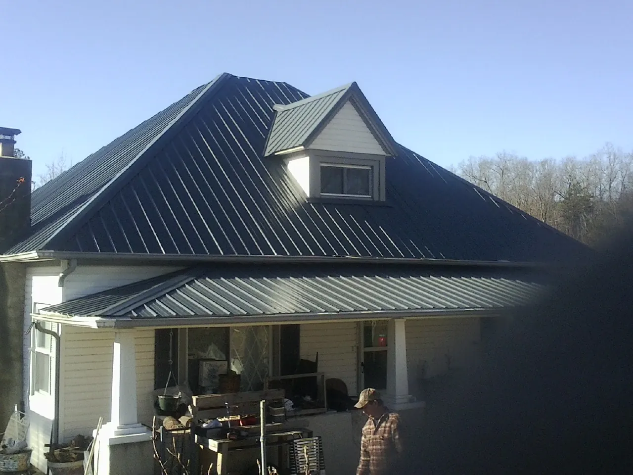 Dark blue standing seam metal roof with a dormer above a front porch in Austinburg