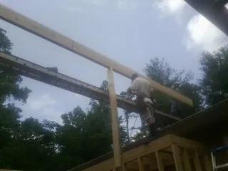 Carpenter setting a ridge beam over a new addition frame — Ice Dam Removal by Roofing Brothers in Austinburg