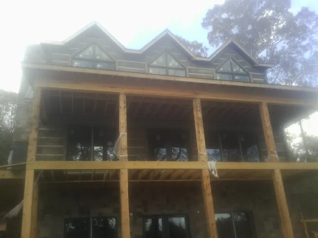Dormers and porch framing on a large log home under construction — Roof Coating work by our crew in Austinburg
