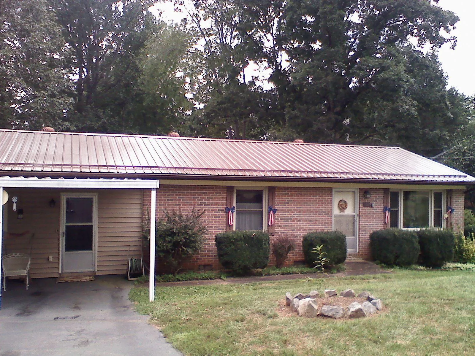 Bronze metal roof and carport on a brick ranch home — Roof Repair work by our crew in Austinburg