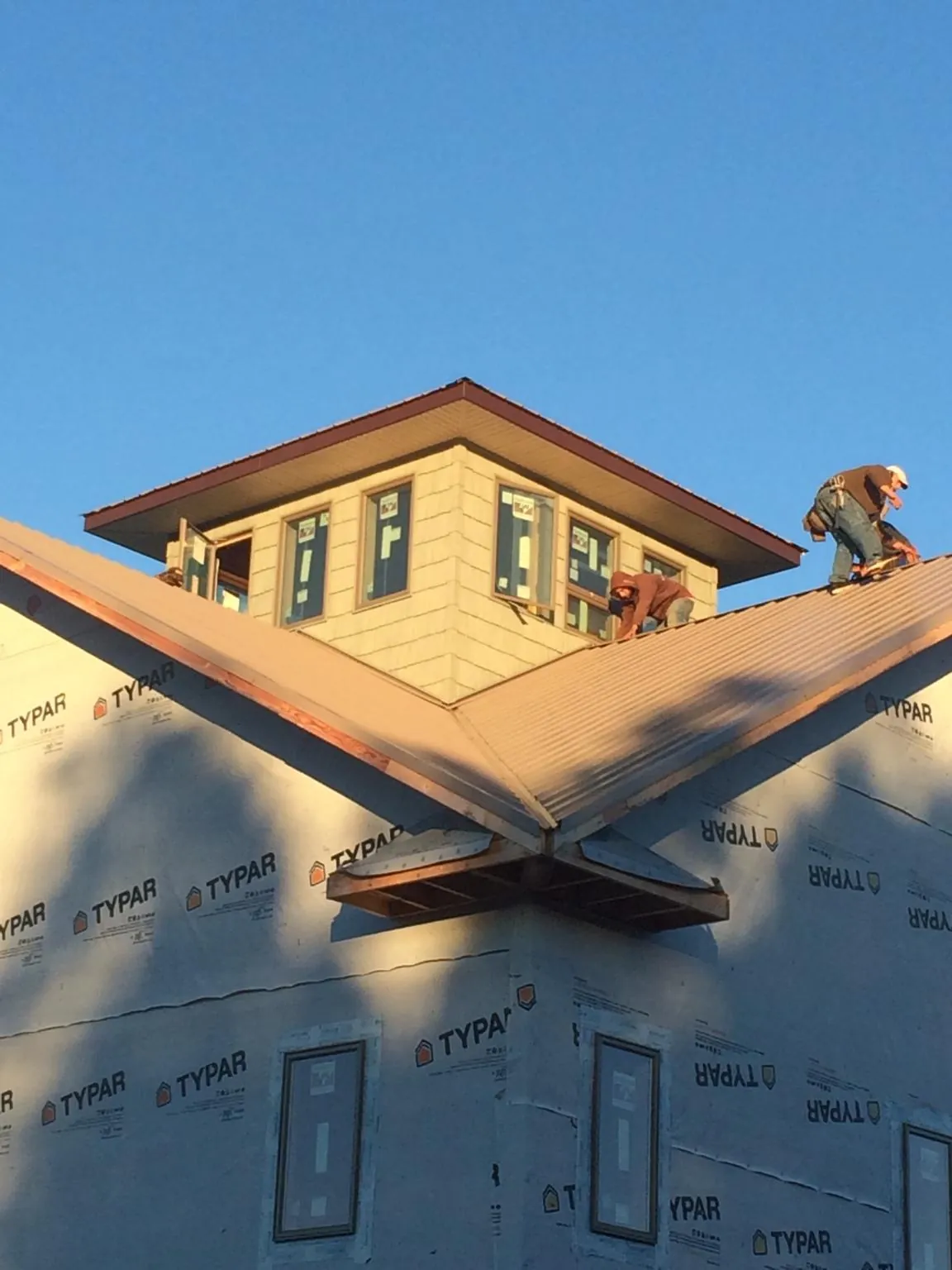 Roofers working around a rooftop cupola on a new metal roof at sunset — Roof Waterproofing in Austinburg by Roofing Brothers